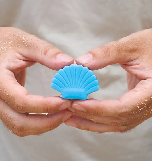 แว็กซ์หอม Ocean Breeze รูปเปลือกหอยสีฟ้า ถือในมือริมชายหาด