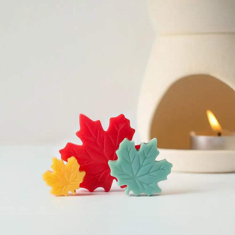 แว็กซ์เมลต์รูปใบเมเปิ้ลหลากสีสันจาก Dalayla วางหน้าเตาอโรมาเซรามิกที่จุดเทียนแล้ว