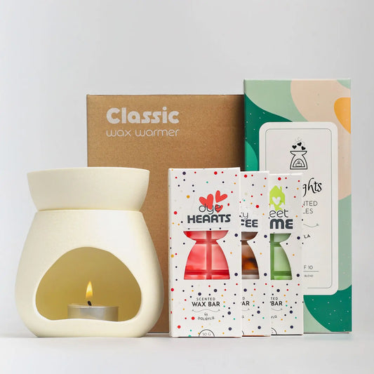รูปภาพเซ็ตสินค้า Ceramic M Bundle ประกอบด้วยเตาอุ่นแว็กซ์เซรามิกสีขาว (Ceramic Wax Warmer) วางคู่กับกล่องแว็กซ์บาร์ 3 กล่อง กลิ่น Dye Hearts, Minty Coffee และ Sweet Home พร้อมด้วยเทียนทีไลท์แบบไม่มีกลิ่นแพ็ก 10 ถ้วย และมีกล่องบรรจุภัณฑ์สีน้ำตาลวางอยู่ด้านหลังเพื่อความสวยงามและพร้อมส่งครับ