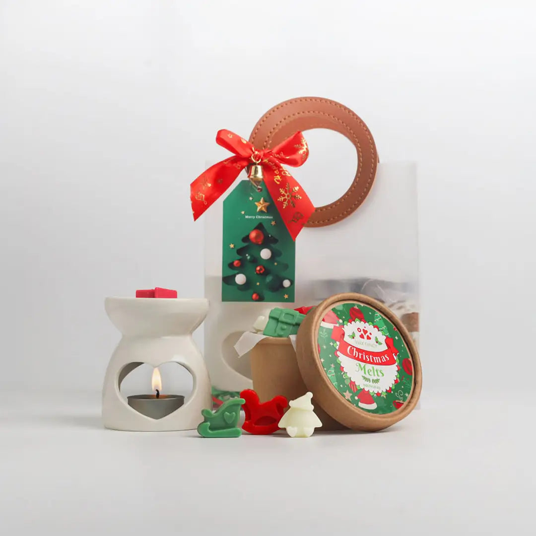 Christmas Gift Set กลิ่น Christmas Melts: เตาอโรมาเซรามิกมินิ กระปุกแว็กซ์หอม และถุงของขวัญใสผูกโบว์แดงพร้อมการ์ด บนพื้นหลังสีขาว