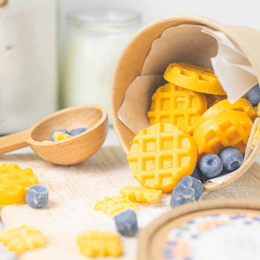 แว็กซ์หอมดีไซน์พิเศษ กลิ่น Blueberry Waffles วางโชว์บนถาดไม้คู่กับถ้วยคราฟท์และช้อนไม้ ตกแต่งมุมห้องสไตล์เบเกอรี่แบรนด์ Dalayla