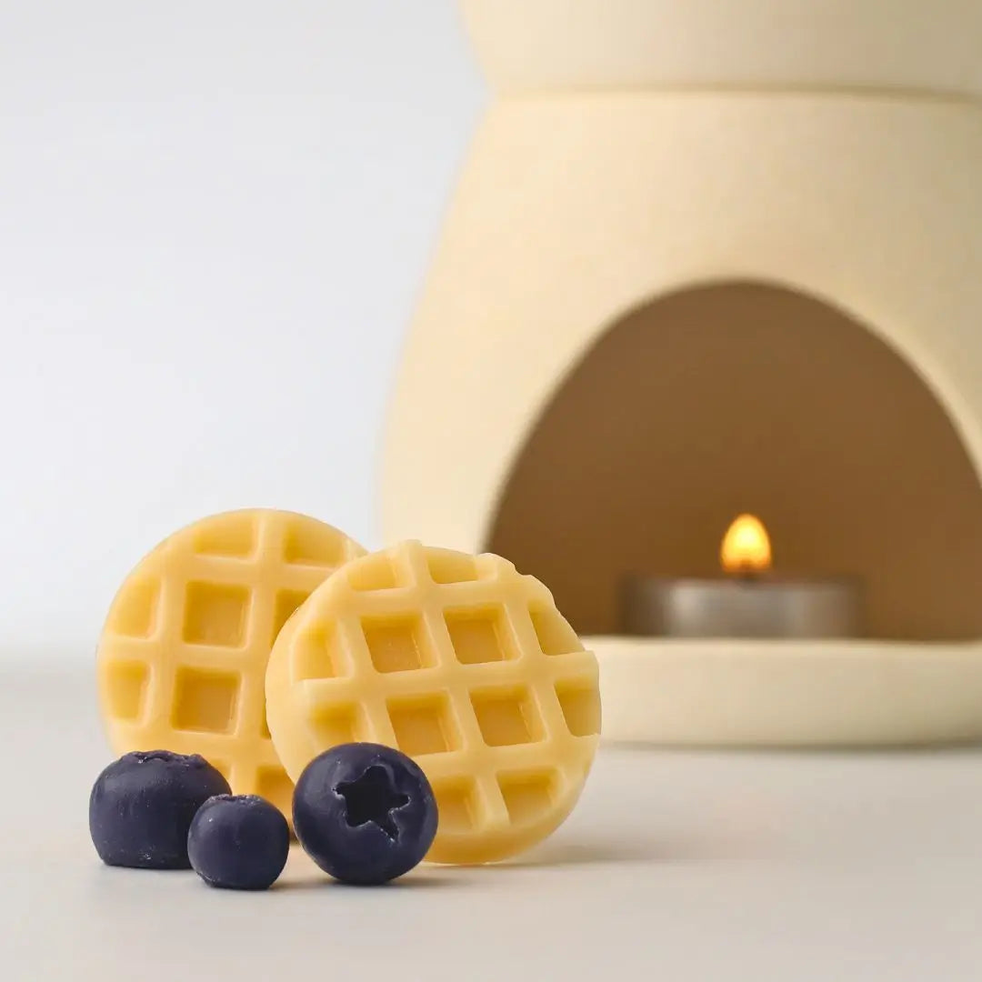 แว็กซ์หอมกลิ่นบลูเบอร์รี่วอฟเฟิล วางคู่กับเตาอโรมาเซรามิกและเทียนทีไลท์ เตรียมพร้อมสำหรับการใช้งานเพื่อสร้างกลิ่นหอมในบ้าน