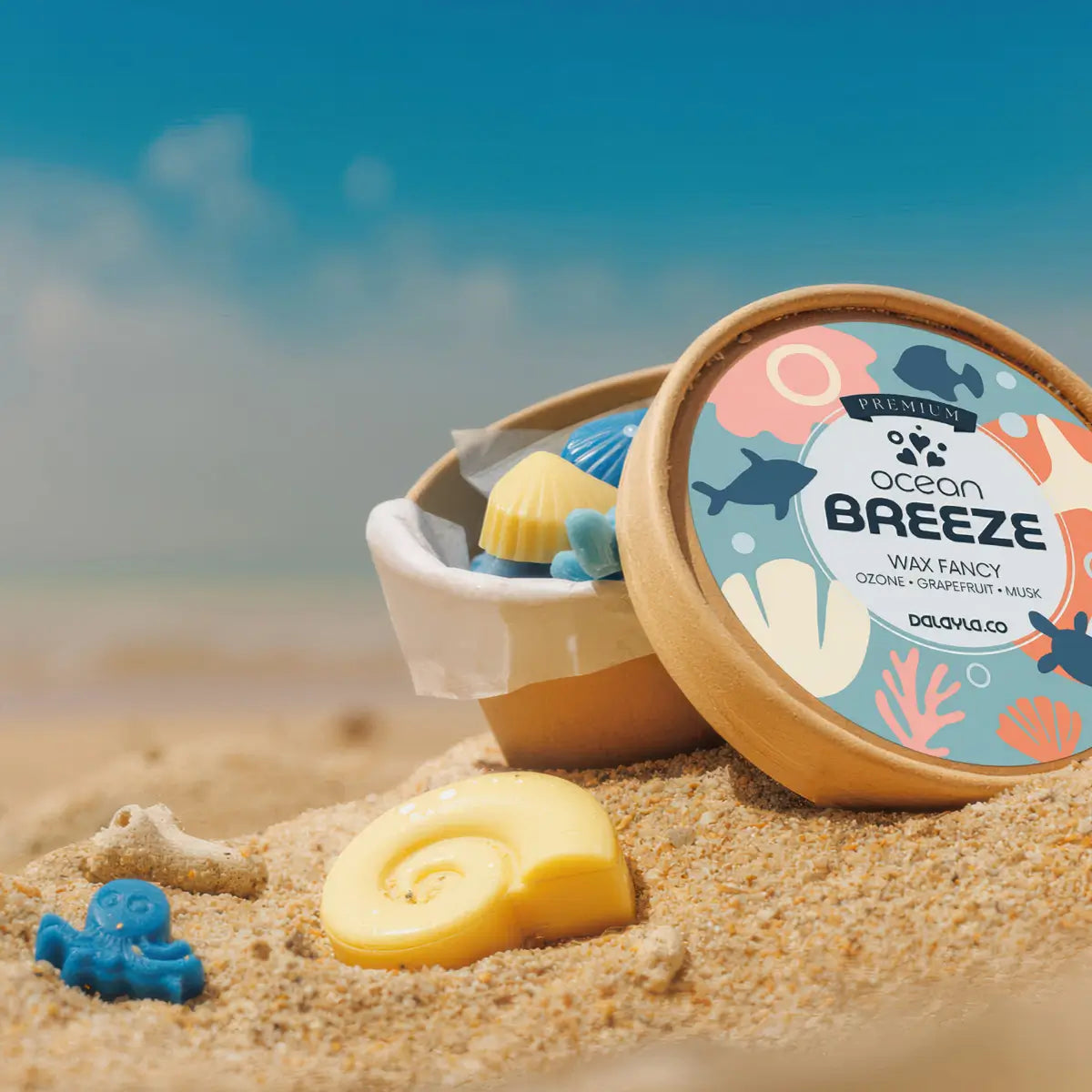 ถ้วยใส่แว็กซ์หอม Ocean Breeze Premium Wax Fancy กลิ่น Ozone Grapefruit Musk พร้อมฉลาก วางบนทราย รายล้อมด้วยแว็กซ์รูปทรงมหาสมุทรต่างๆ เปลือกหอย และปะการัง พร้อมพื้นหลังทะเลเลือนลาง